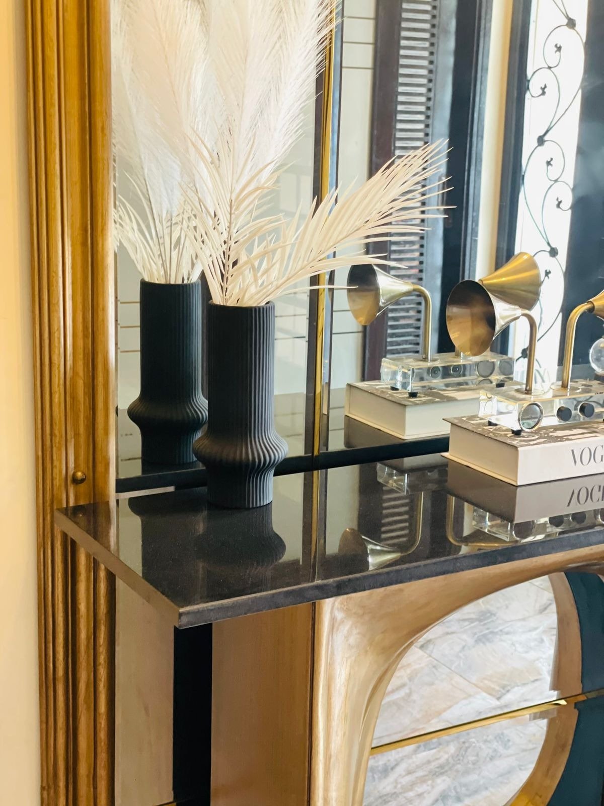 Detail of black fluted vases and brass gramophone speakers on a console table